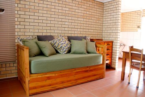 a wooden couch with pillows on a brick wall at Vita Nova in Bloemfontein