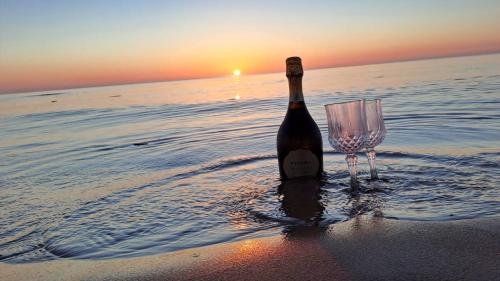 a bottle of wine and a wine glass on the beach at Hirsihuvila Villa Letto, pihasauna & ulkoporeamme in Kalajoki