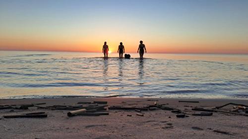 three people standing in the water at the beach at Hirsihuvila Villa Letto, pihasauna & ulkoporeamme in Kalajoki