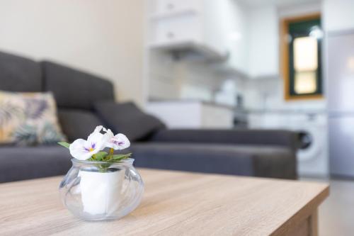 a glass vase with flowers sitting on a table at Apartagal-Costa Reinante Spa in Barreiros