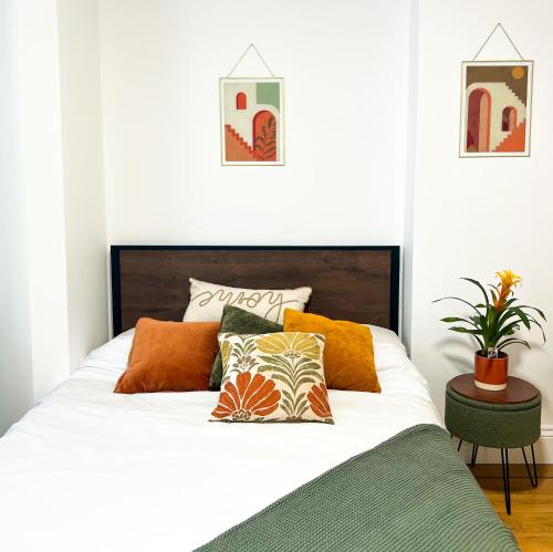 a bedroom with a bed with orange and green pillows at Happy Land in London