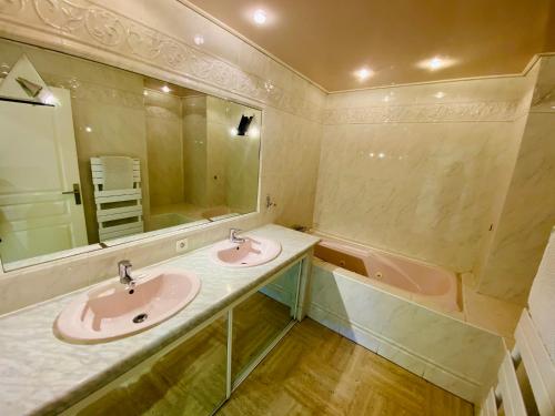 une salle de bain avec deux lavabos et une baignoire dans l'établissement ''Le cadre royal'' appartement de standing sur quai avec parking, à Sète
