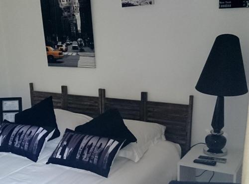 a bed with black and white pillows and a lamp at Hotel La Bastie d'Urfé in Naussac