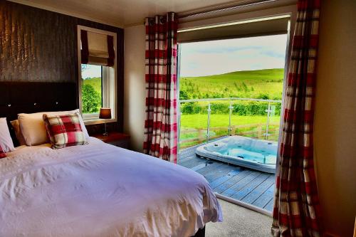 a bedroom with a bed and a balcony with a tub at Arbennig Luxury Lodges in Mold