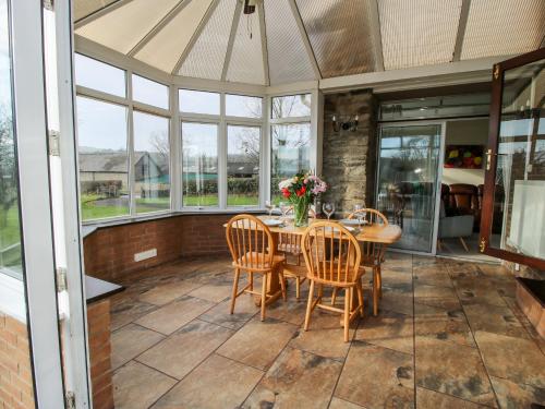a conservatory with a table and chairs and windows at Bicton Lea in Acton
