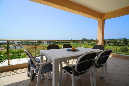 a white table and chairs on a balcony with a view at Makridis Summer Villas in Paralía Avdhíron