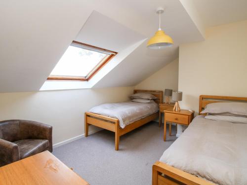 a attic bedroom with two beds and a chair at Bicton Lea in Acton