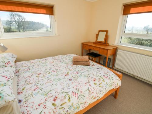 a bedroom with a bed and a desk and two windows at Bicton Lea in Acton