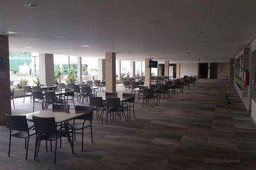 an empty cafeteria with tables and chairs and a television at Park Veredas Flat Service in Rio Quente