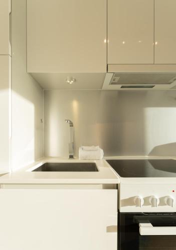 a white kitchen with a sink and a stove at Stylish Aparthotel in Tórshavn in Tórshavn