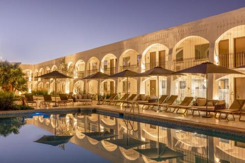 un hotel con piscina, sillas y sombrillas en Gamma Ciudad Juarez en Ciudad Juárez