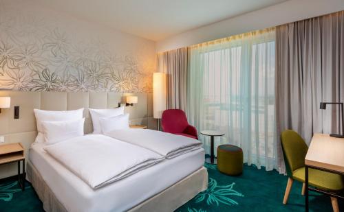 a hotel room with a bed and a desk and a window at Mövenpick Hotel Stuttgart Messe & Congress in Stuttgart