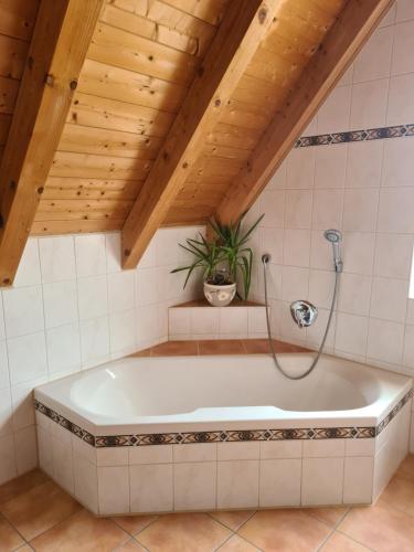a bath tub in a bathroom with a wooden ceiling at Ferienwohnung Helga in Thalmässing