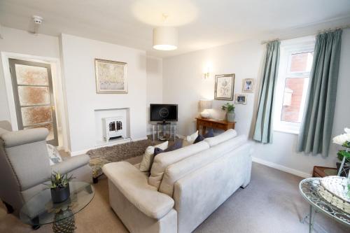 a living room with a couch and chairs and a tv at The Old School House in Lytham St Annes