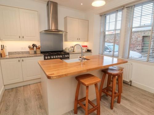 eine Küche mit weißen Schränken und einer hölzernen Arbeitsplatte in der Unterkunft Iona 10 Palace Street East in Berwick-Upon-Tweed