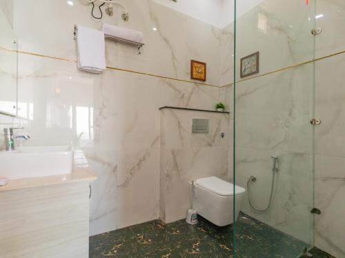 a bathroom with a shower and a toilet and a sink at SaffronStays Niyama, Dehradun in Dehradun