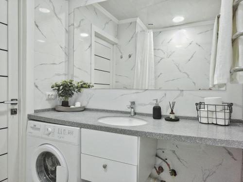 - une buanderie blanche avec lave-linge et sèche-linge dans l'établissement Студия КОЛОС в центре с шикарным видом из окна, à Almaty