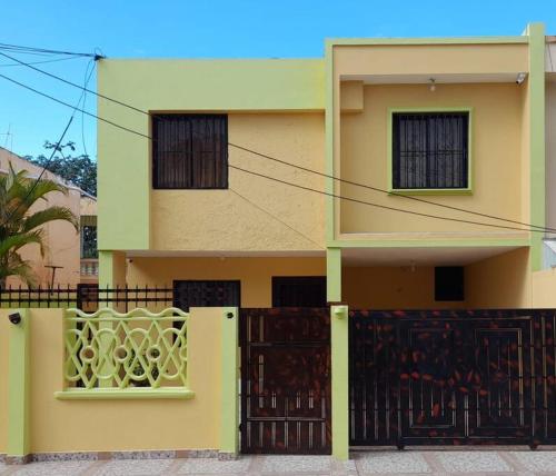 una casa amarilla con una puerta y una valla en casa equipada estadia placentera, en Hainamosa