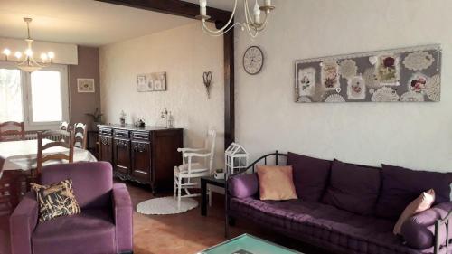 a living room with a purple couch and a dining room at Gîte Le bel Epi in Vany