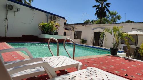a swimming pool with two chairs next to a house at Apartamentos Villa Leonor in Coveñas