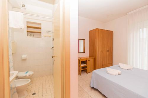 a bathroom with a bed and a toilet and a sink at Hotel Arlino in Rimini