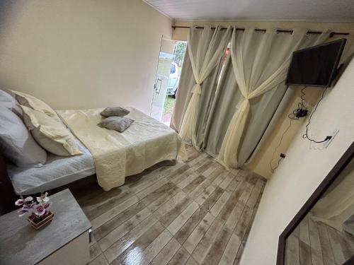 Dormitorio pequeño con cama y TV en Pousada Sal da Terra en Carrancas