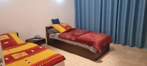 a bedroom with two twin beds and blue curtains at New Marina Appartement Susi in Hurghada