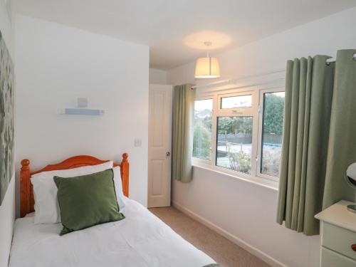 a bedroom with a bed and a window at Honeysuckle Cottage in Paignton