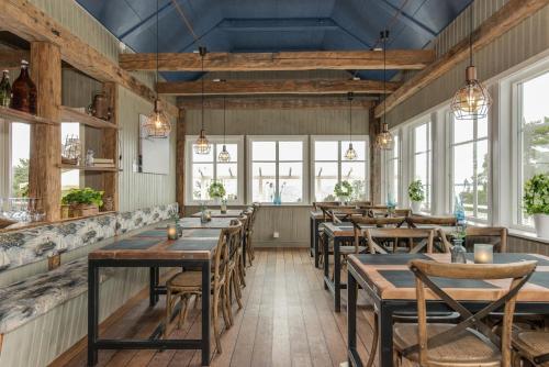 um restaurante com mesas e cadeiras de madeira e janelas em First Camp Duse Udde - Säffle em Säffle