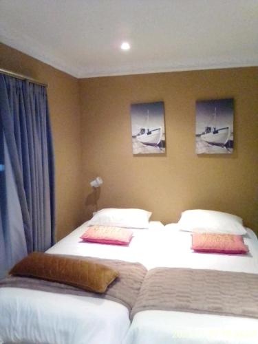 two beds in a hotel room with pictures on the wall at Mkhandi Self Catering in Durban