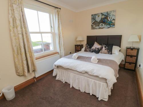 ein Schlafzimmer mit großem Bett und Fenster in der Unterkunft Home Stead Cottage in Embleton