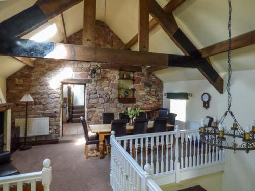 a living room with a table and chairs and a stone wall at Meadow Place in Ipstones