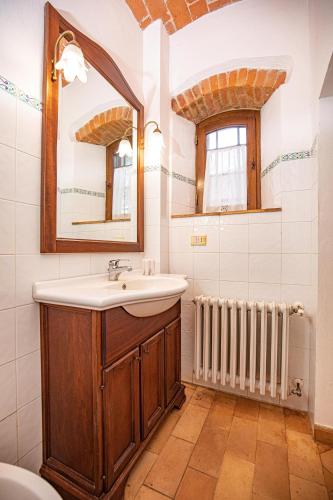 a bathroom with a sink and a mirror and a radiator at Affitti Brevi Toscana - Ospitalità in Campagna in Talamone