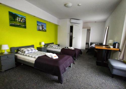 a hotel room with three beds and a yellow wall at RJ Hotel in Pabianice