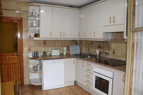 una cocina con armarios blancos y fregadero en Casa Rural La Callejuela en Ayllón