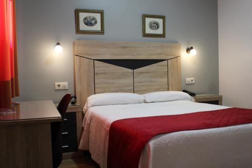 a bedroom with a large bed with a wooden headboard at Hostal Madrid in Toledo