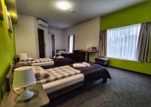 a hotel room with two beds in a room with green walls at RJ Hotel in Pabianice