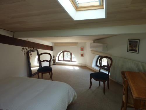 a bedroom with a bed and two chairs and a table at Beaux Chênes in Nérac