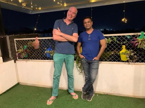 two men standing on a balcony with their arms crossed at Xcel Luxury Hotel Apartments-Home Living Redefined in Mysore
