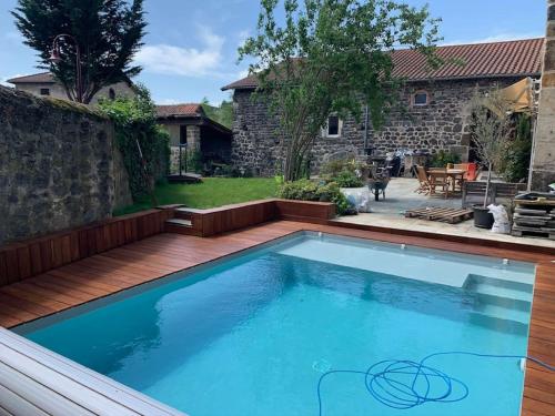 a swimming pool in a backyard with a wooden deck at Ferme rénovée avec Piscine in Polignac