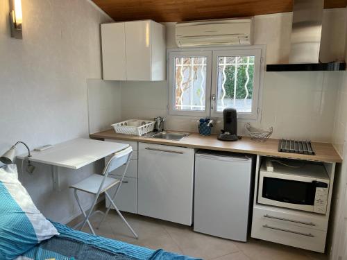 une petite cuisine avec un évier et un micro-ondes dans l'établissement Studio indépendant, à Roquettes