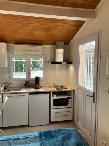 une cuisine avec des armoires blanches et un comptoir dans l'établissement Studio indépendant, à Roquettes