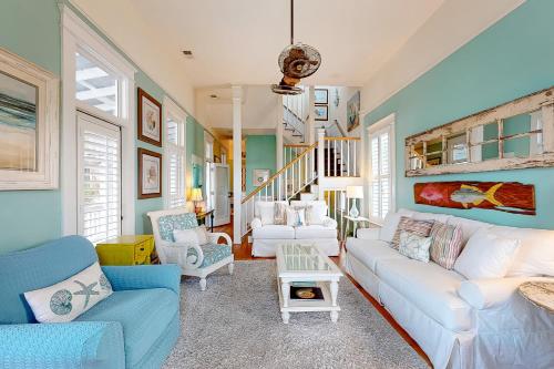 a living room with a white couch and chairs at True Knot Cottage in Saint Simons Island