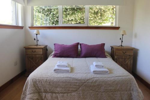 1 dormitorio con 1 cama con almohadas moradas y 2 ventanas en Casaquinta La Morena en Azul