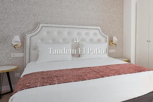 a bedroom with a white bed with a sign on it at Tandem El Patio in Córdoba