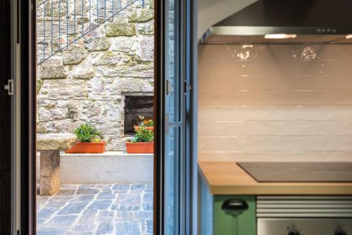 a sliding glass door with a window with a stone fireplace at Feel Discovery Homes in Douro in Peso da Régua