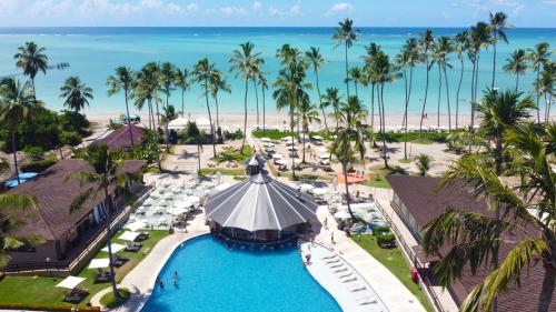 uma vista aérea de uma piscina de resort com palmeiras e da praia em Grand Oca Maragogi All Inclusive Resort em Maragogi