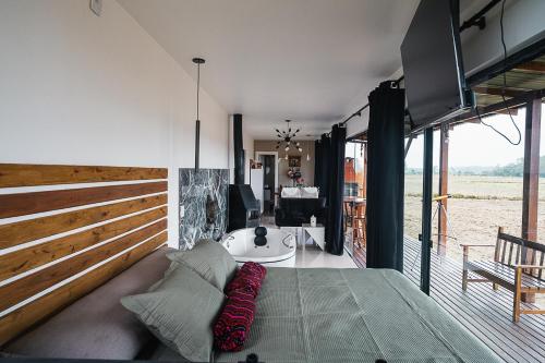 een kamer met een bed, een bank en een aantal ramen bij CASA DE VIDRO EM MEIO A NATUREZA - Conteiner Lua in Piçarras