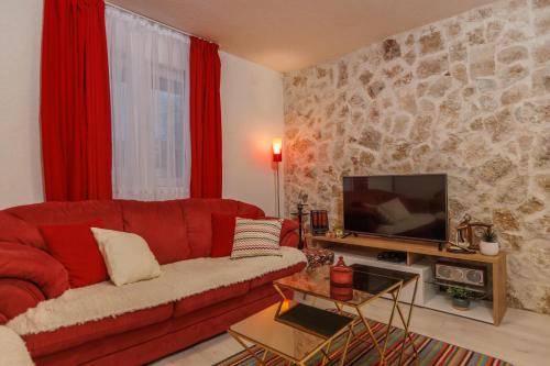 a living room with a red couch and a tv at Family SPA Apartments Sunny&Shiny in Šavnik
