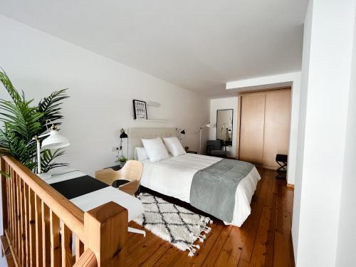 a white bedroom with a bed and a staircase at Apartamentos Ciudad Santiago in Santiago de Compostela